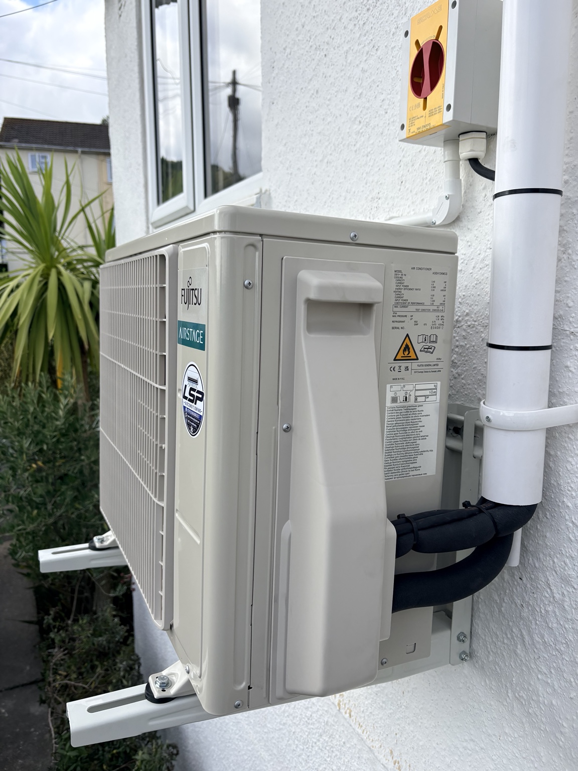 Outdoor unit and pipework by a white wall